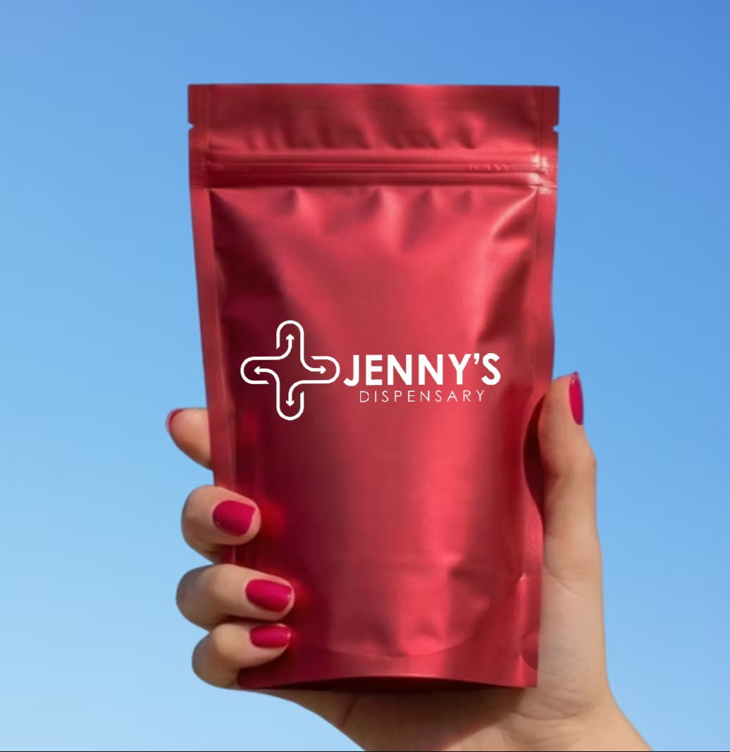 A hand holding a red Jenny's Dispensary mylar bag against a blue sky
